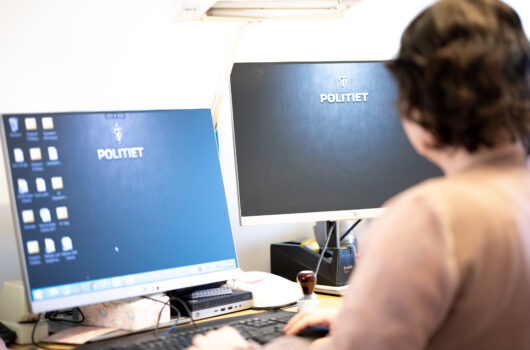 Sivilt ansatt på kontor foran PC med politet på skjerm