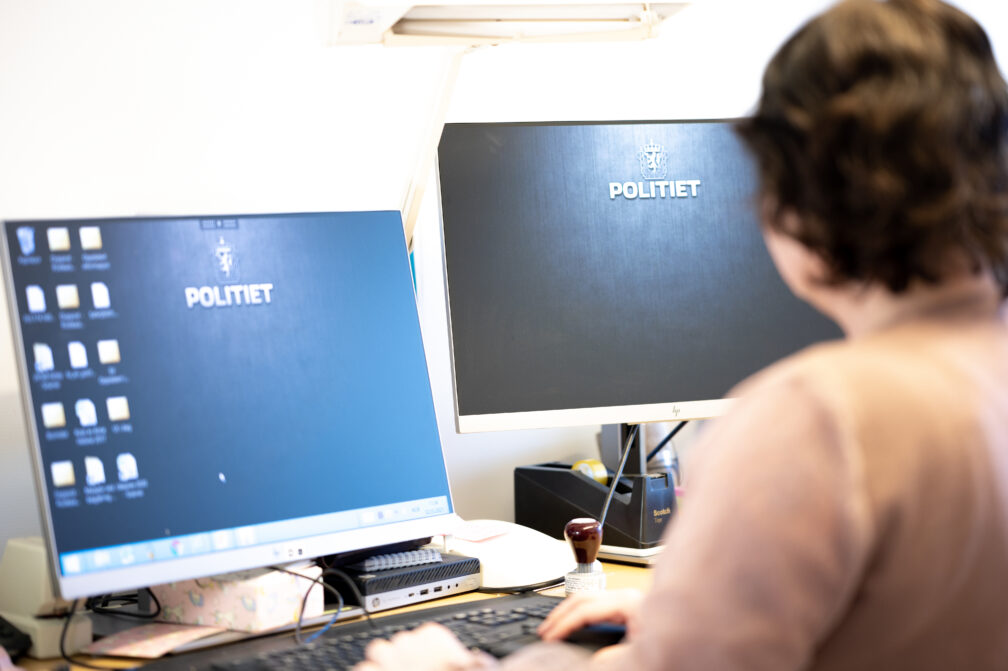 Sivilt ansatt på kontor foran PC med politet på skjerm