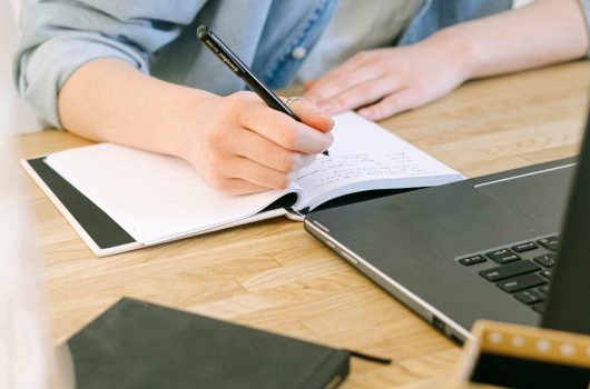 Person som tar notater ved en PC studerer studier kurs stipend (beskjært)