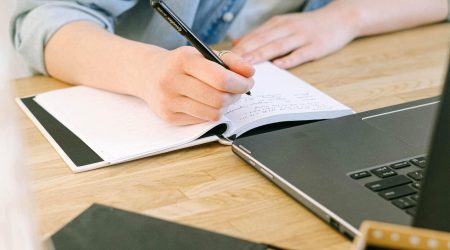 Person som tar notater ved en PC studerer studier kurs stipend (beskjært)